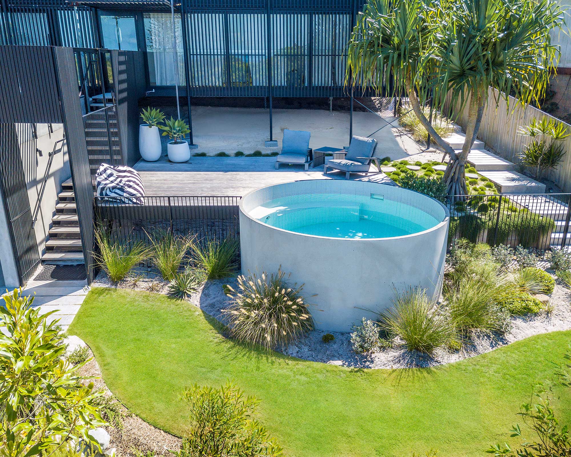 Modern multi-level backyard with circular plunge pool surrounded by drought-tolerant plants, contemporary furniture, and modern minimalist architecture